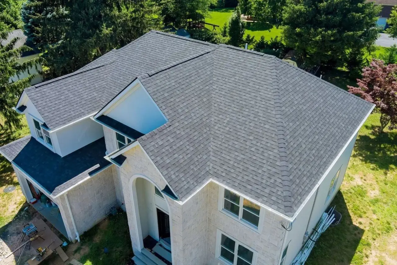 Aerial view of a freshly installed architectural shingle roof on a stone-faced home