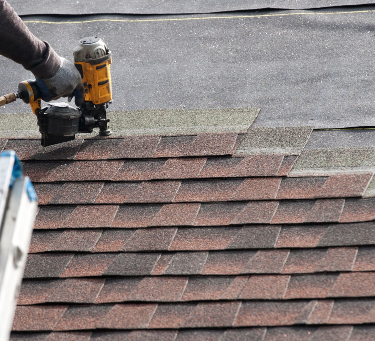Nail gun on red asphalt shingles during installation