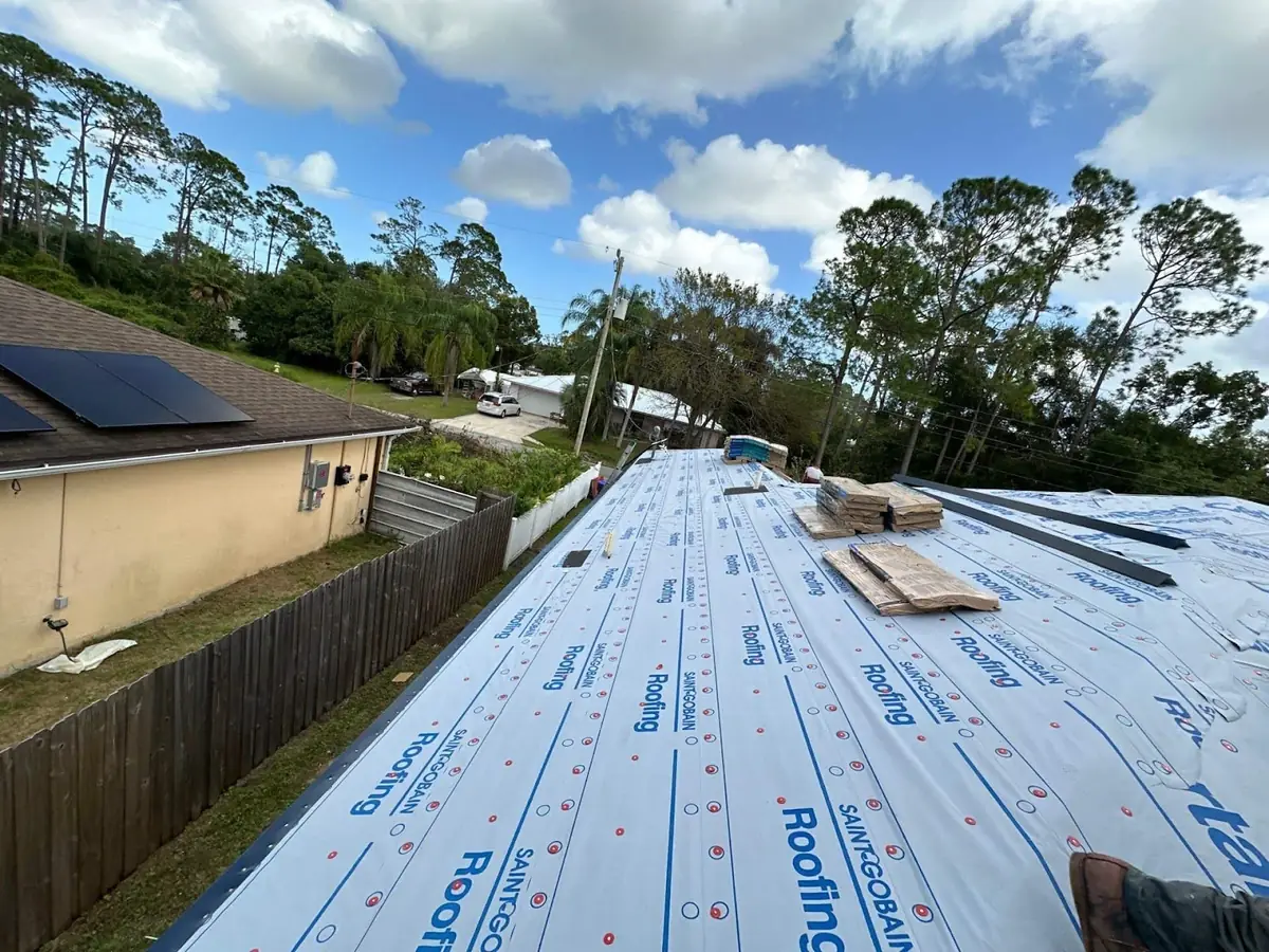 Synthetic underlayment rolled out over a roof deck during a reroof
